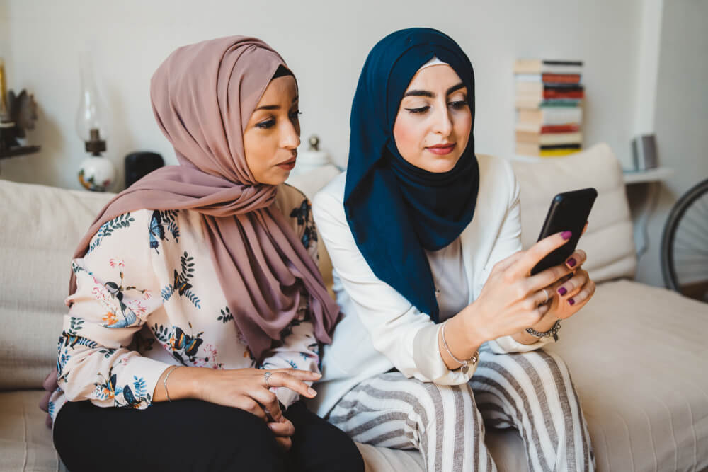 Two Egyptian women looking at a smartphone together, illustrating social media use and digital habits in Egypt.
